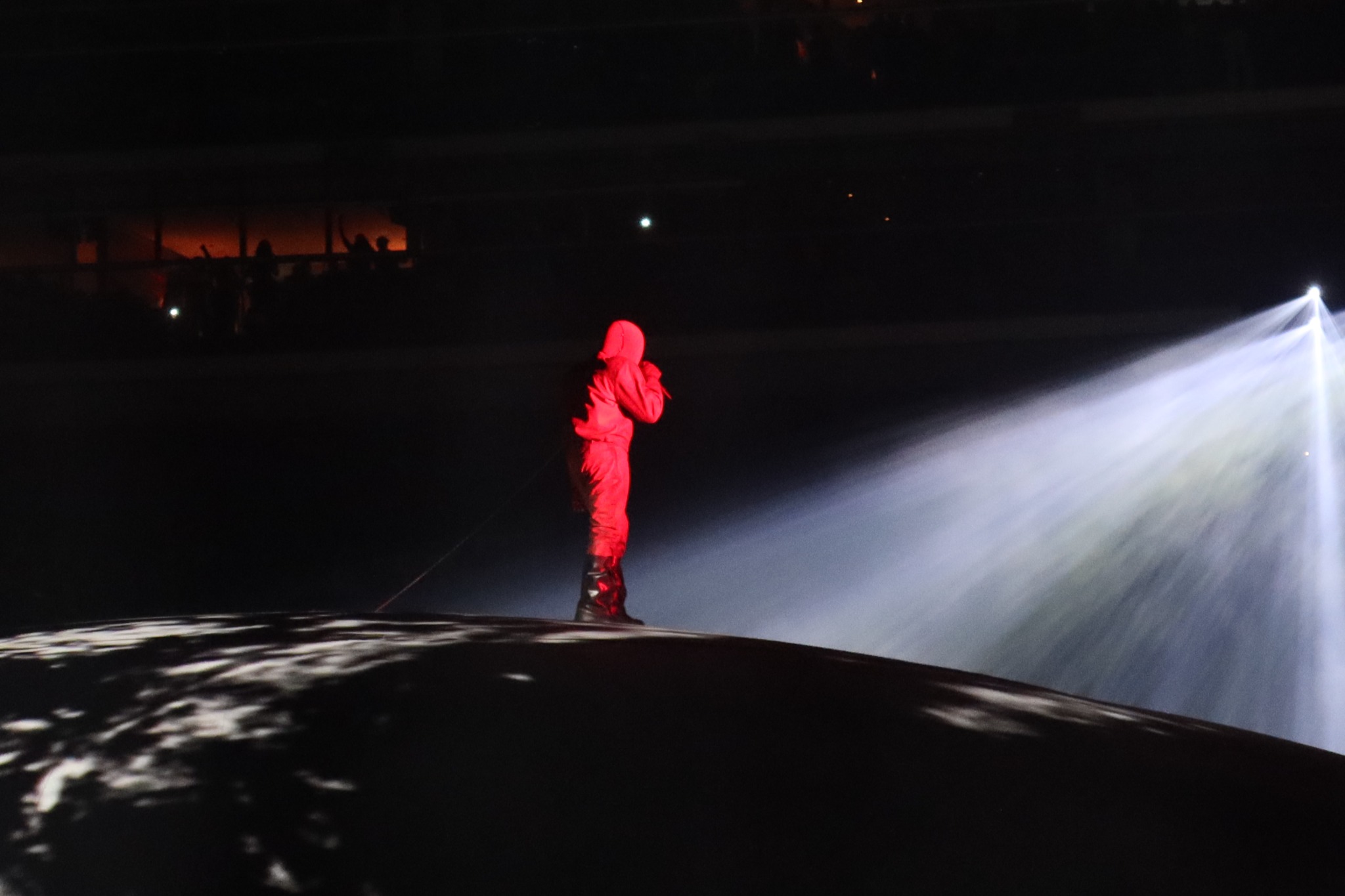 A performer in red beside a bright stage beam