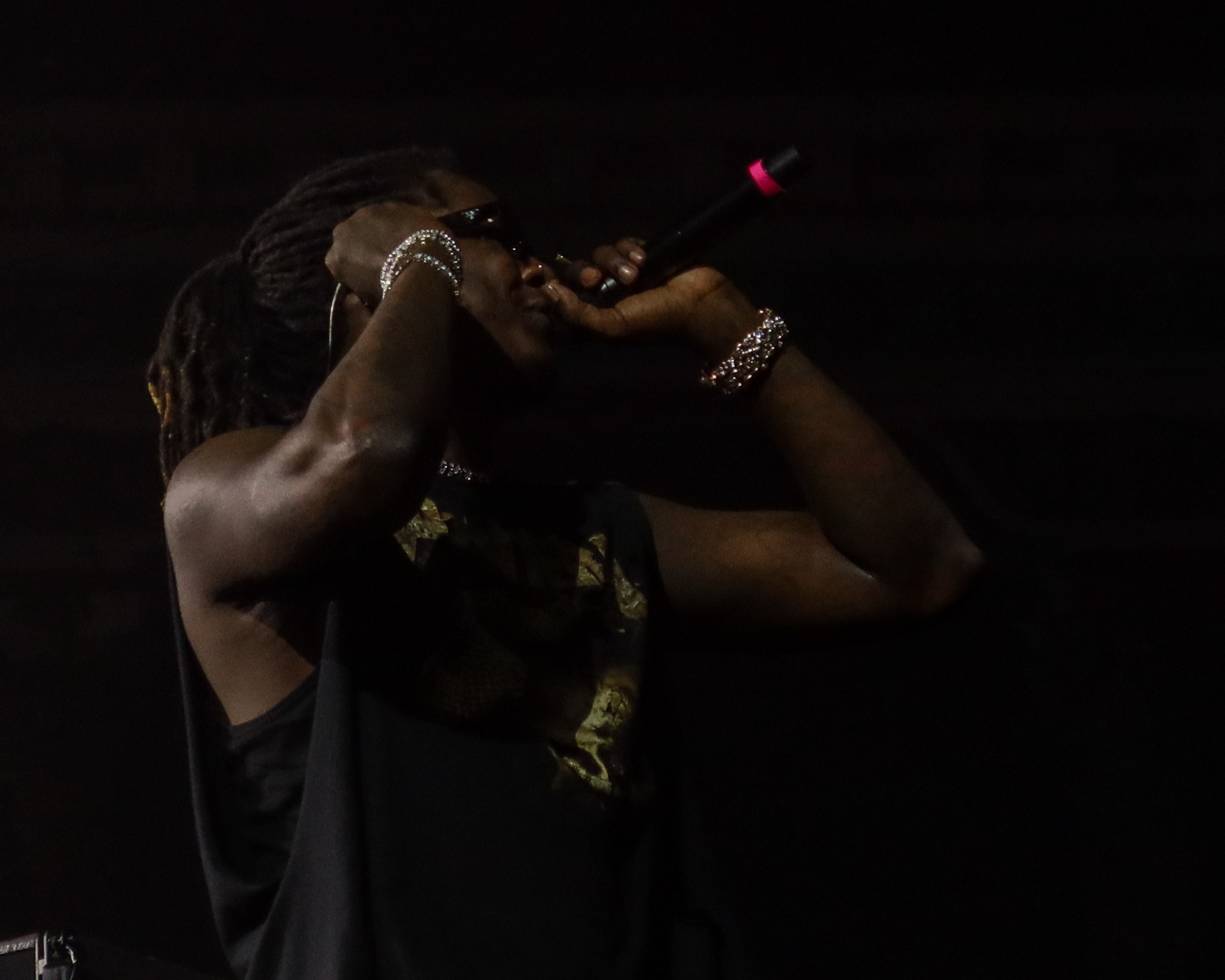 Young Thug singing under dark stage lighting