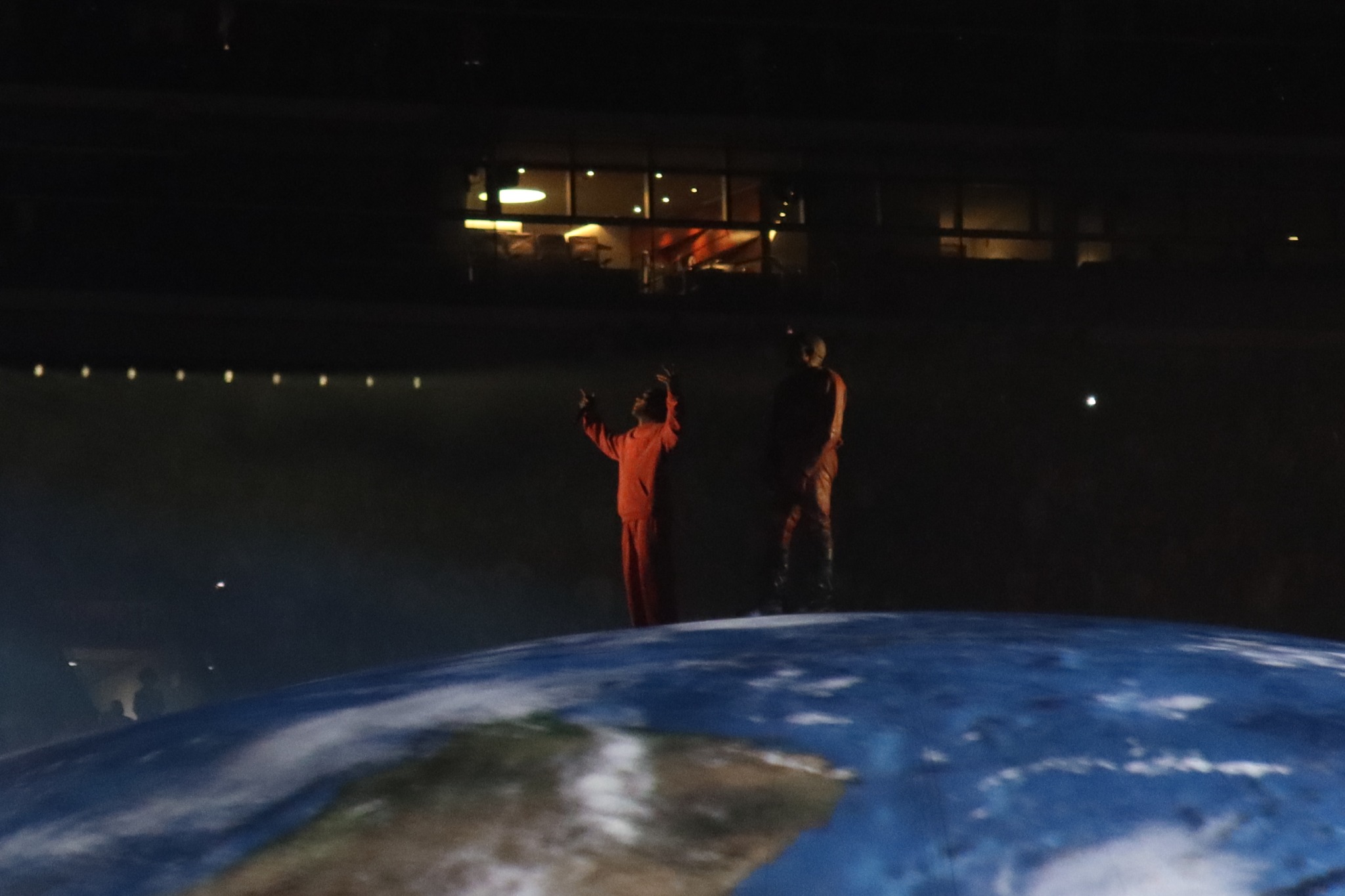 Two performers standing above the projected globe